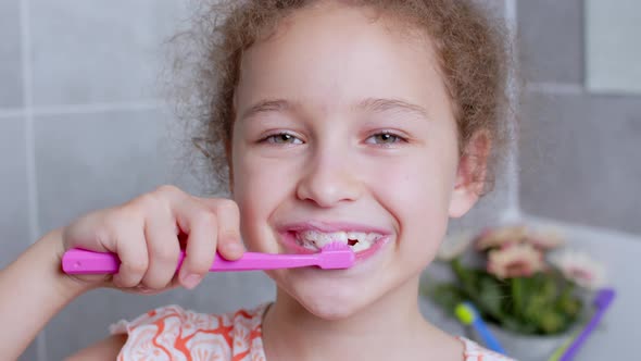 Portrait Happy Cute Young Teenage Girl Brushing Teethin the Morning in Bathroom and Smiling