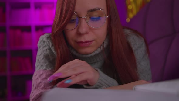 A Beautiful Student with Glasses Reading a Big Book