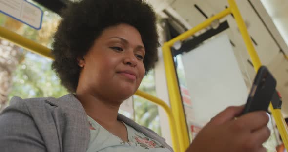 Happy plus size biracial woman using smartphone in bus
