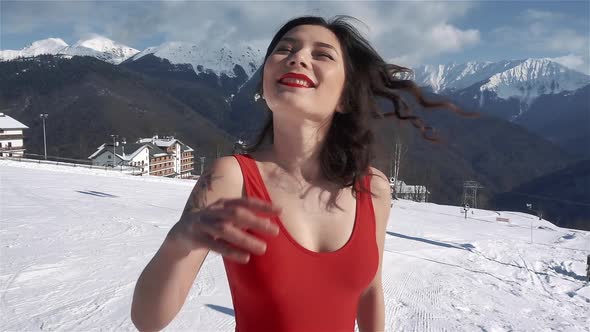Pretty Young Asian Woman with Bright Make Up and in Red Swimsuit at Winter Ski Resort at Snowy Sunny