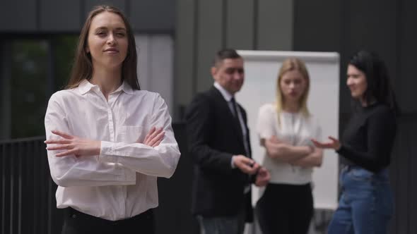 Portrait of Confident Arrogant Woman Crossing Hands Looking at Camera Ignoring Colleagues Mocking at