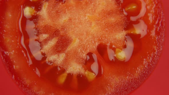 Slice of Cherry Tomato Rotating on Red Background. Close Up