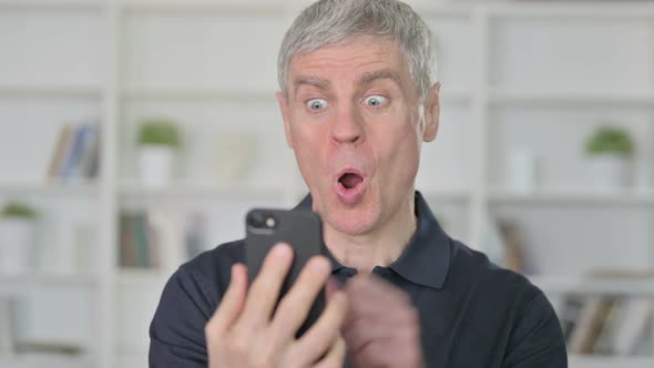 Middle Aged Businessman Celebrating Success on Smartphone