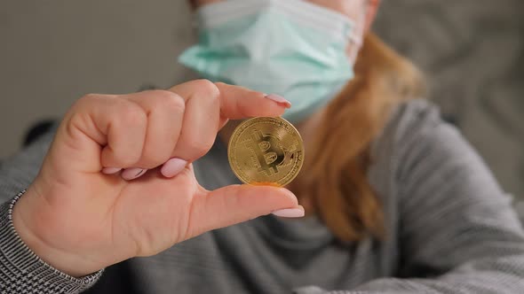 Closeup of a Business Lady in a Medical Mask Holding a Bitcoin Coin