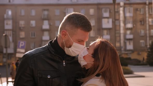 Couple in Medical Masks Standing Embracing on a Street in the City