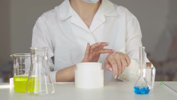 Scientist applying cream on her hand for testing of skincare products.