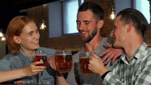 Happy Young People Clinking Their Beers and Smiling To the Camera