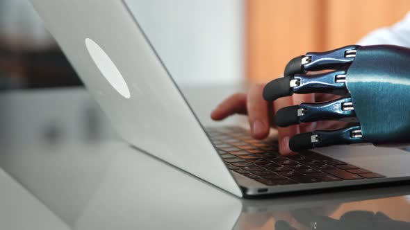 Programmer man hands with artificial bio prothesis type on laptop keyboard on table