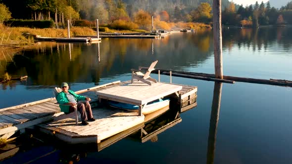 Man sitting on dock at sunset