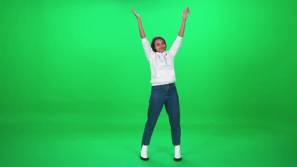 Young African Woman Dancing at a Music Concert Dance and Claps Their Arms on a Green Background