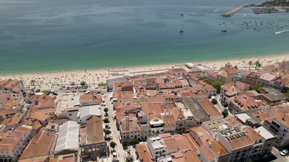 Aerial backward ascendent over Sesimbra coastal city with port in background, Portugal