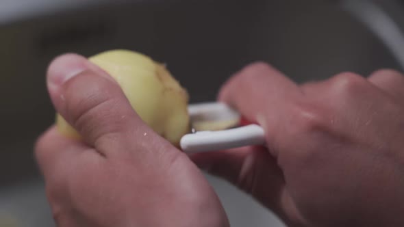Husband Peels Potatoes with a Tool for Cleaning Vegetables and Making Dinner
