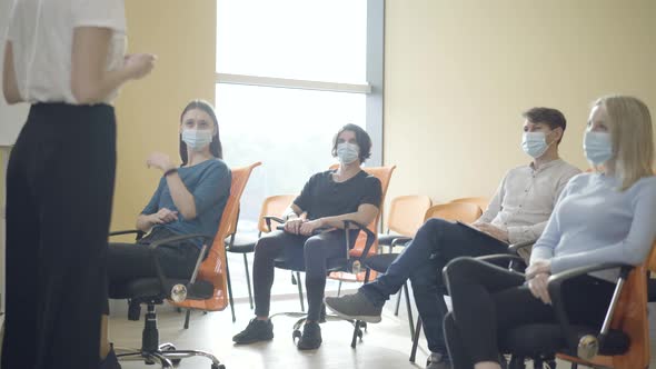 Unrecognizable Female Tutor Talking To Group of Adult Caucasian People Sitting in Auditorium