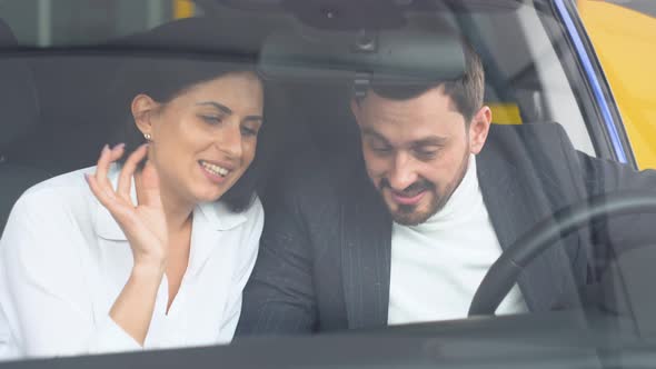 Elegant Man Sitting in Car Salon and Talking with Female Car Dealer