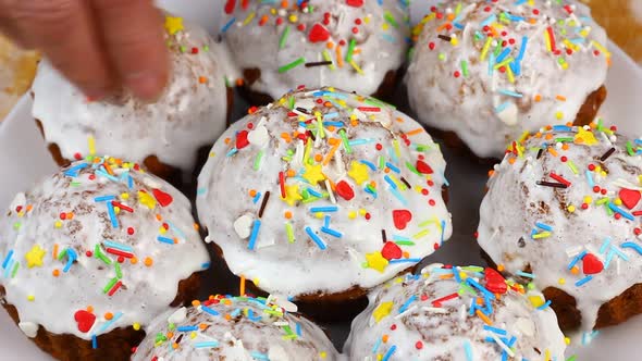 Woman Decorates Small Easter Cupcakes with White Frosting Pours Sweet Decor Nonparelle on Them