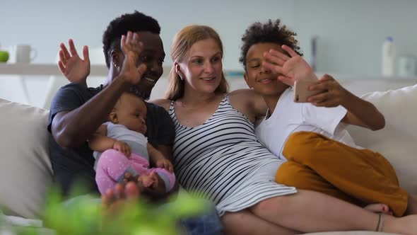 Young African Multiracial Family with Children Taking Selfie Photo on Couch in Apartment Interior