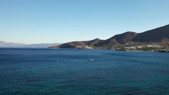 Aerial View of a Speeding Motor Boat in a Deep Blue Colored Sea. Spinalonga Island, Crete, Greece