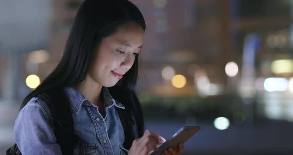 Woman watching on mobile phone in city at night