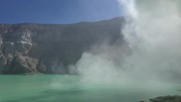 Aerial view of flying above acidic lake and toxic sulfur gas clouds at the crater of Kawah Ijen