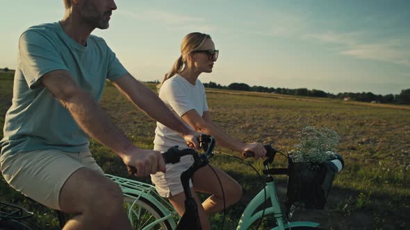 Cheerful caucasian couple of middle age riding a bike on sunset on village road. Shot with RED heliu