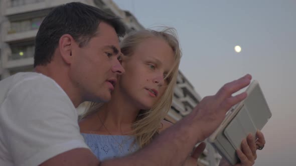 Couple with Pad on Sea-front in the Evening