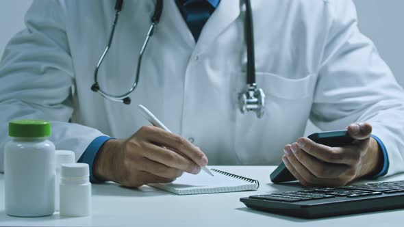 Arab Male Doctor Therapist in Modern Clinic Wearing White Coat Uniform Using Cell Mobile Smartphone