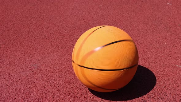 Basketball ball spinning on red outdoors court