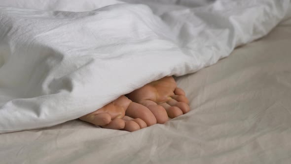 Sleepy Person Covered with Blanket Wriggles Toes in Bed