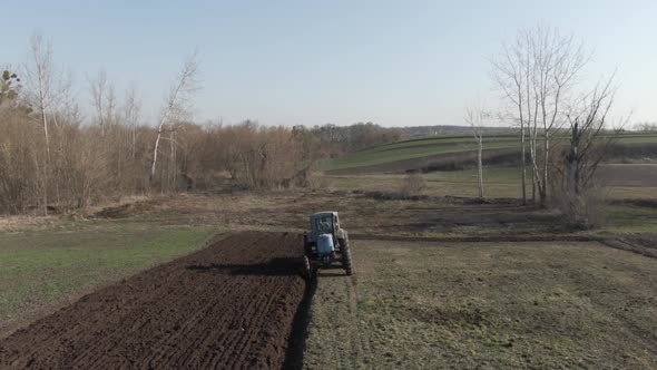 Camera Follows Tractor Furrowing Fertile Field