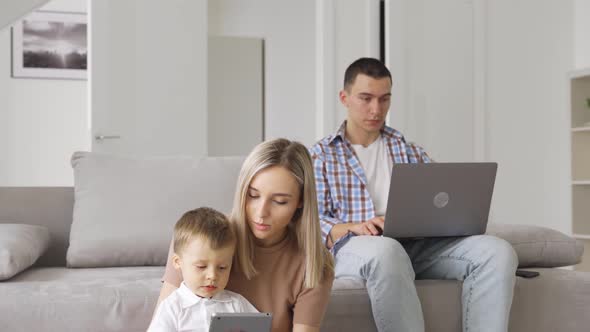 Happy Family Mom Dad and Child Son Using Laptop and Digital Tablet at Home