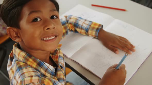 Portrait of boy sitting at his desk in classroom