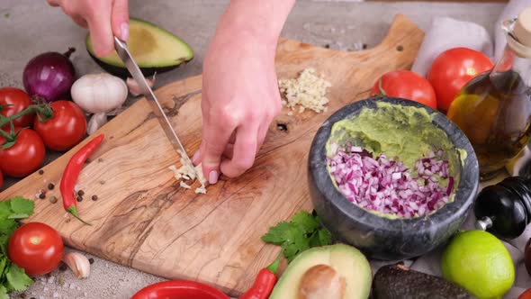 Making Guacamole Sauce  Woman Chopping Garlic on a Wooden Cutting Board