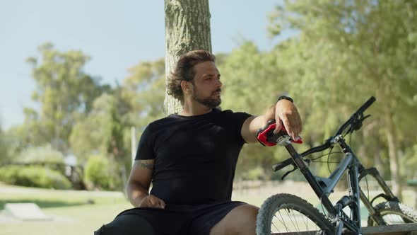 Cheerful Man with Bionic Leg Relaxing on Bench After Cycling