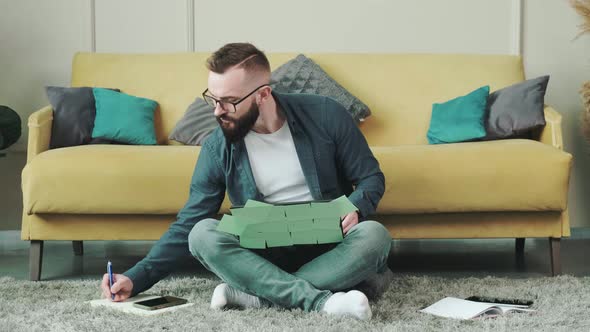 Man Working at the Computer with a Lot of Reminder Notes Sitting Near Sofa