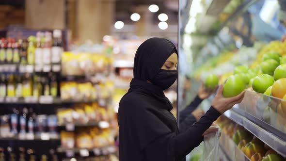 Muslim Women Shopping for Groceries Taking Fruits From the Shelf Side View