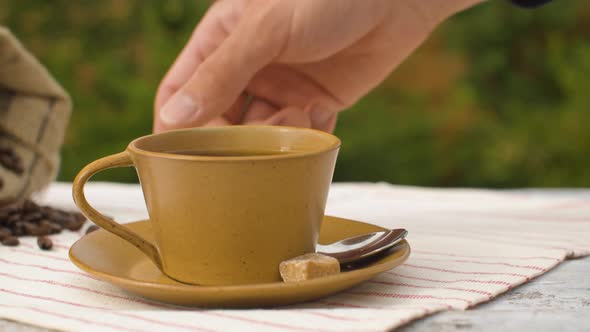 Hand puts sugar into a cup of coffee