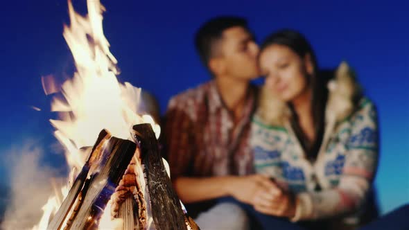 On the Beach, Lit a Fire in the Background Blurred Young Couple Embracing