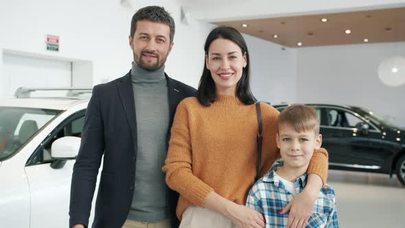 Slow Motion of Happy Family with Son Smiling in Car Dealership Standing Together