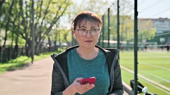 Active Mature Woman in Sportswear with Smartphone Outdoor