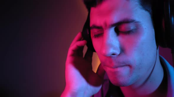 Portrait Man Relaxes Listening to Music Through Headphones in Neon Lighting