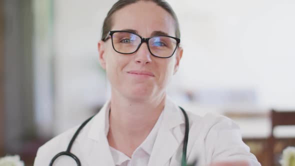 Portrait of happy caucasian female doctor holding green awareness ribbon