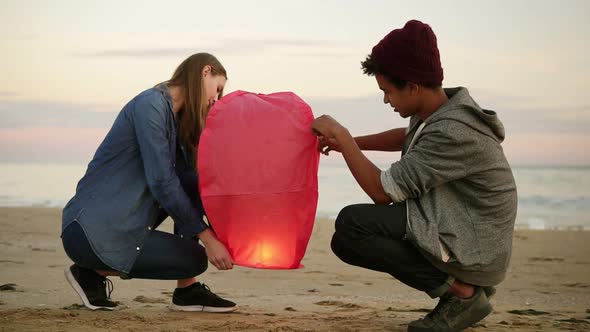 Cute Multiethnic Couple Holding Red Paper Lantern Before Launching