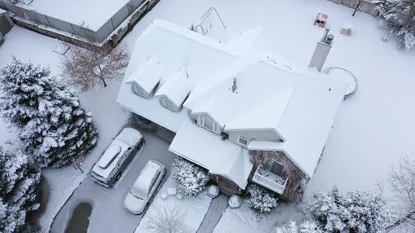 Aerial view flying down looking at house covered in snow