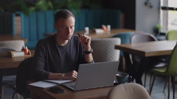 Thoughtful Serious Young Man Student Writer Sit at Home Office Desk with Laptop Thinking of