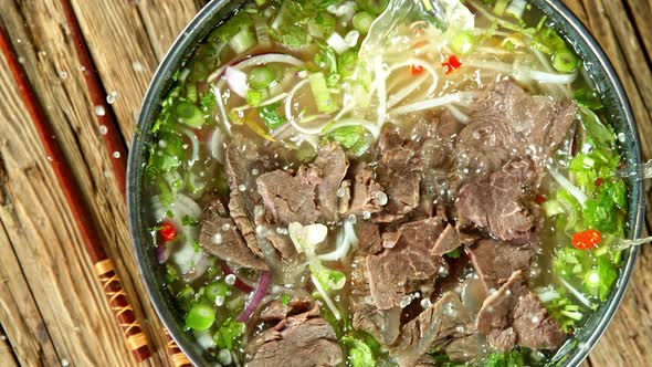 Super Slow Motion Detail Shot of Sliced Beef Falling Into Pho Soup at 1000 Fps.