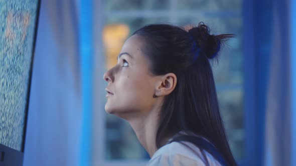 Side View of Young Woman Eating Popcorn and Watching Tv with Noise on Screen