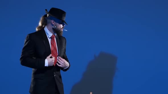 Elegant Man in a Black Hat Is Dancing an Erotic Dance. Spotlight on a Blue Background. Close Up