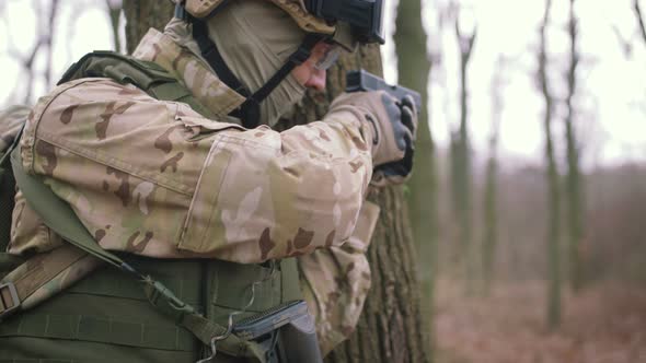 Armed Young Man in a Zone of Armed Conflict in Uniform Targeting with Pistol in Forest Slow Motion