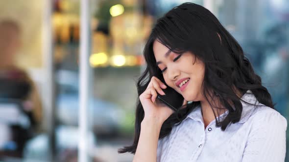 Smiling Asian Businesswoman Having Break Talking Using Smartphone