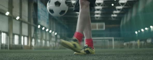Legs of Male Soccer Player Training with Ball on Indoor Field